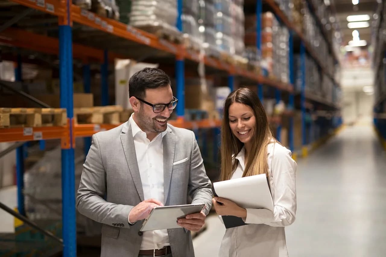 Two people checking stock in a warehouse aisle